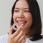 Woman smiling while holding clear aligner