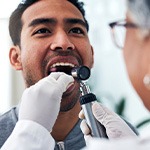 A dentist screening a man for oral cancer