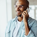 Man with glasses smiling while talking on phone