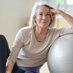 Senior woman smiling while resting against balance ball