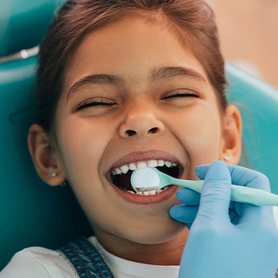 Little girl laughing after dental sealant placement