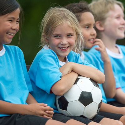 Girl with healthy smile thanks to children's dentistry playing soccer