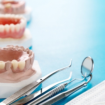 Models of different dentures next to dental tools
