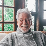 Man in grey sweater sitting and smiling in cabin