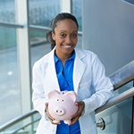 smiling dentist holding a piggy bank 