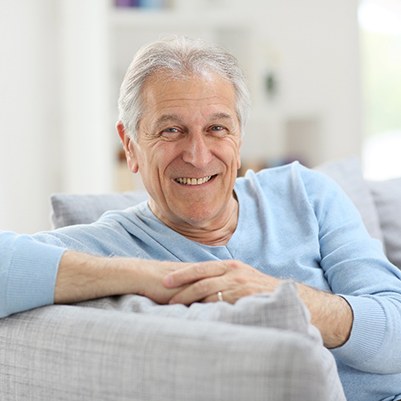 Man sitting and smiling with implant dentures in Frisco, TX