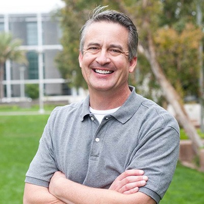 man smiling with arms crossed outside