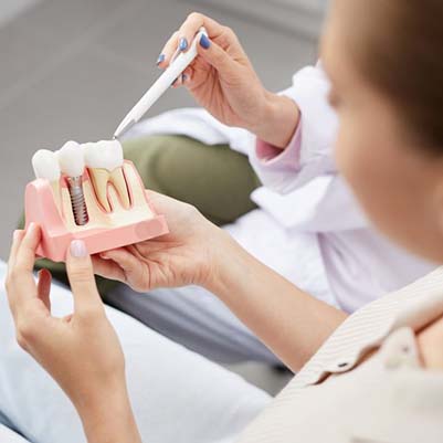 dentist showing a patient a model of a dental implant