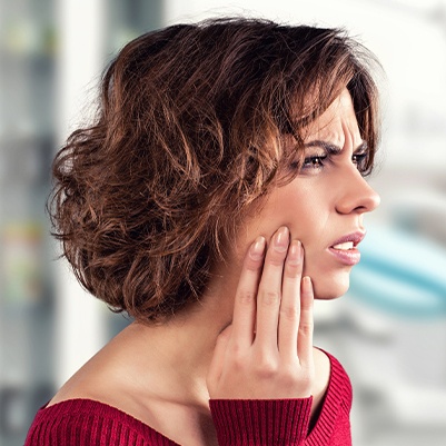 Woman who needs to replace missing teeth holding jaw