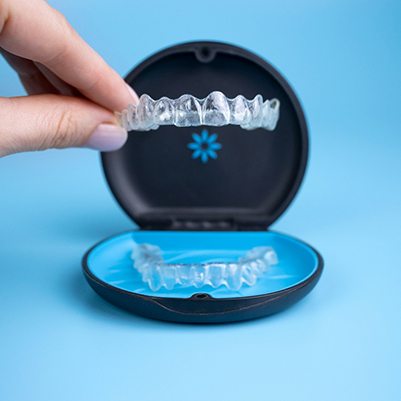 Patient placing Invisalign clear aligner in storage case