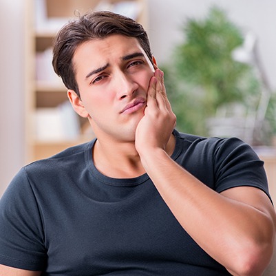 Man in need of root canal therapy holding jaw