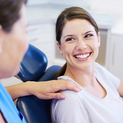 Woman in dental chair smiling after root canal therapy