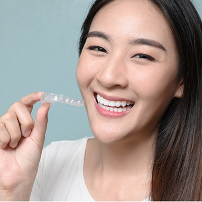 Woman smiling while holding clear aligner