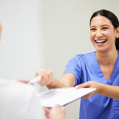 Dental assistant smiling while handing patient form