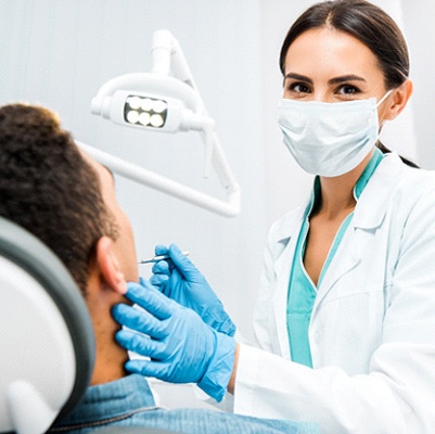 Dentist smiling while conducting procedure