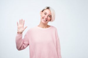 Smiling woman waves at her Frisco, TX dentist during COVID-19