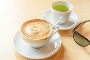 cup of green tea next to a cup of coffee