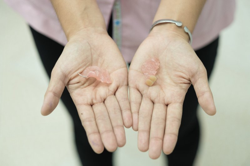 closeup of person holding broken denture