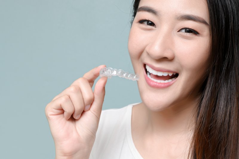 person smiling and holding Invisalign tray